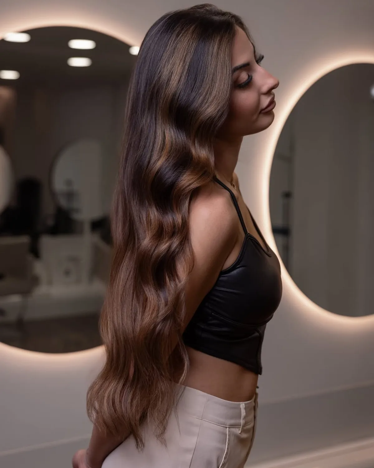 Melena larga morena iluminada con balayage en tonos caramelo, vista de perfil